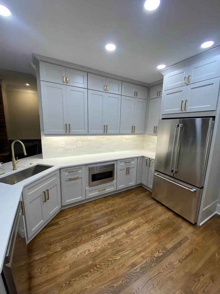 Modern kitchen with white cabinetry, stainless steel appliances, white subway tile backsplash, and wood flooring